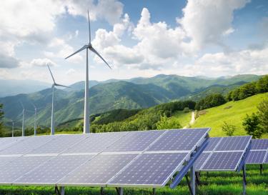 Mountains with solar panels and wind turbines in foreground